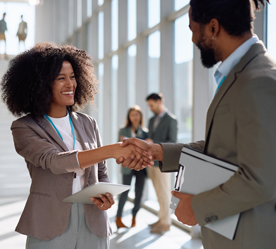 A woman shakes the hand of a man, both smiling.