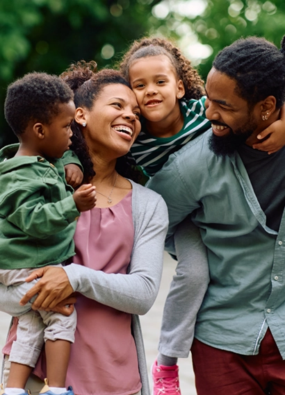 A mother and father holding their children in their arms smiling at each other.